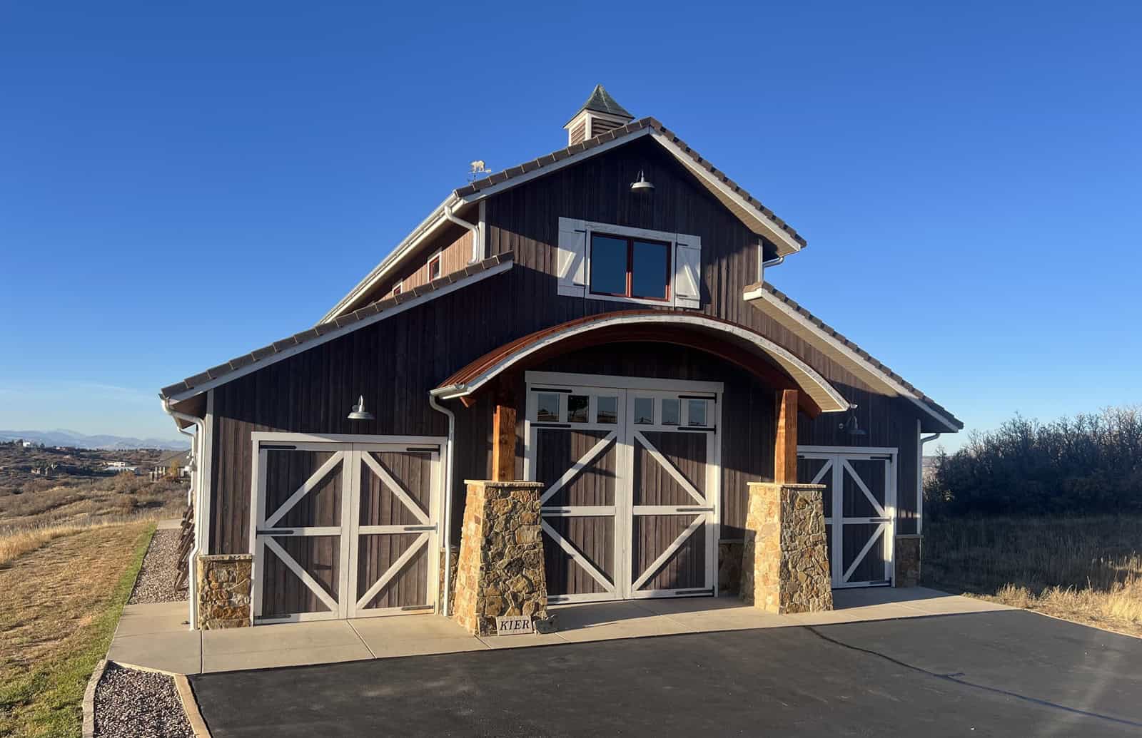 A rustic garage apartment with stone accents, wood siding, and a covered front porch. 1 bed, 660 sq ft — Plan #161-1284.