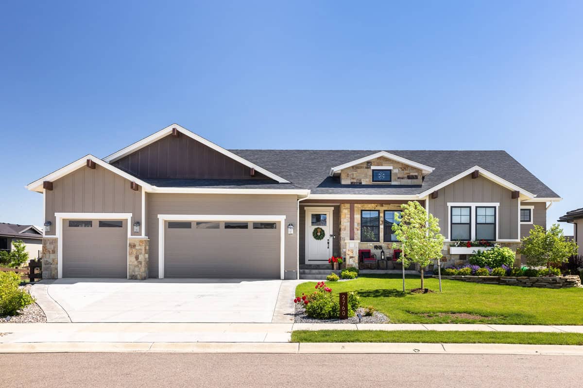 Craftsman ranch facade with board-and-batten siding, stone accents, covered front porch, gable dormers. Plan #161-1340.