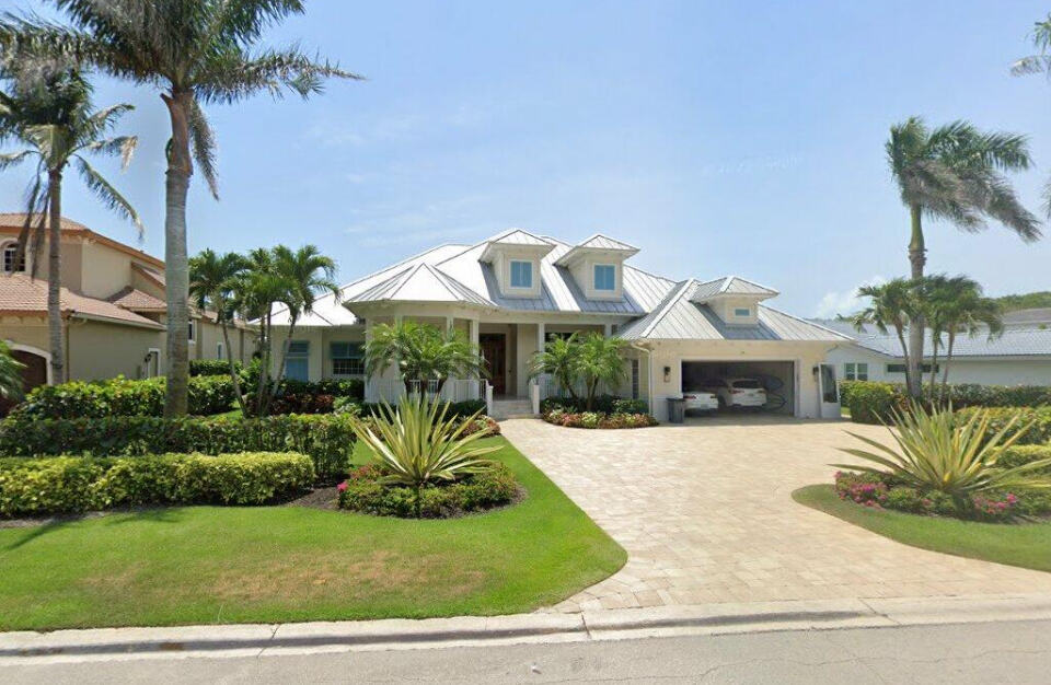 Southern-style home with covered pool deck, 2-car garage, and palm-lined landscaping