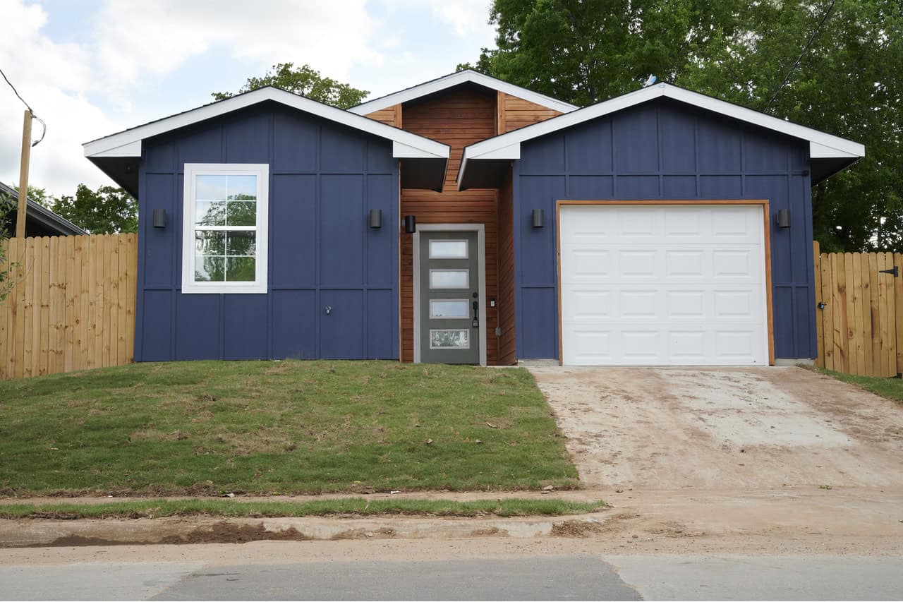 Front exterior of a 1,243 sq ft modern bungalow with 1-car garage and simple, clean architectural lines