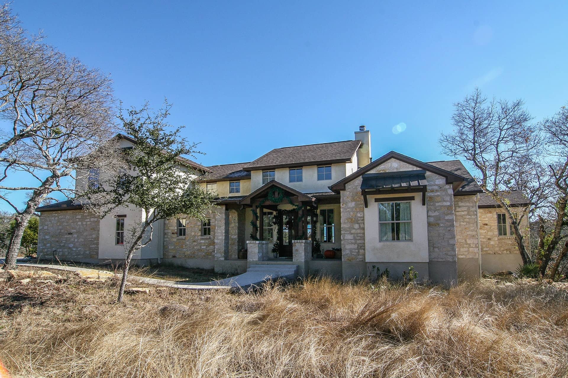 Exterior front view of Texas-style 4-bedroom home with wraparound porch and gabled rooflines
