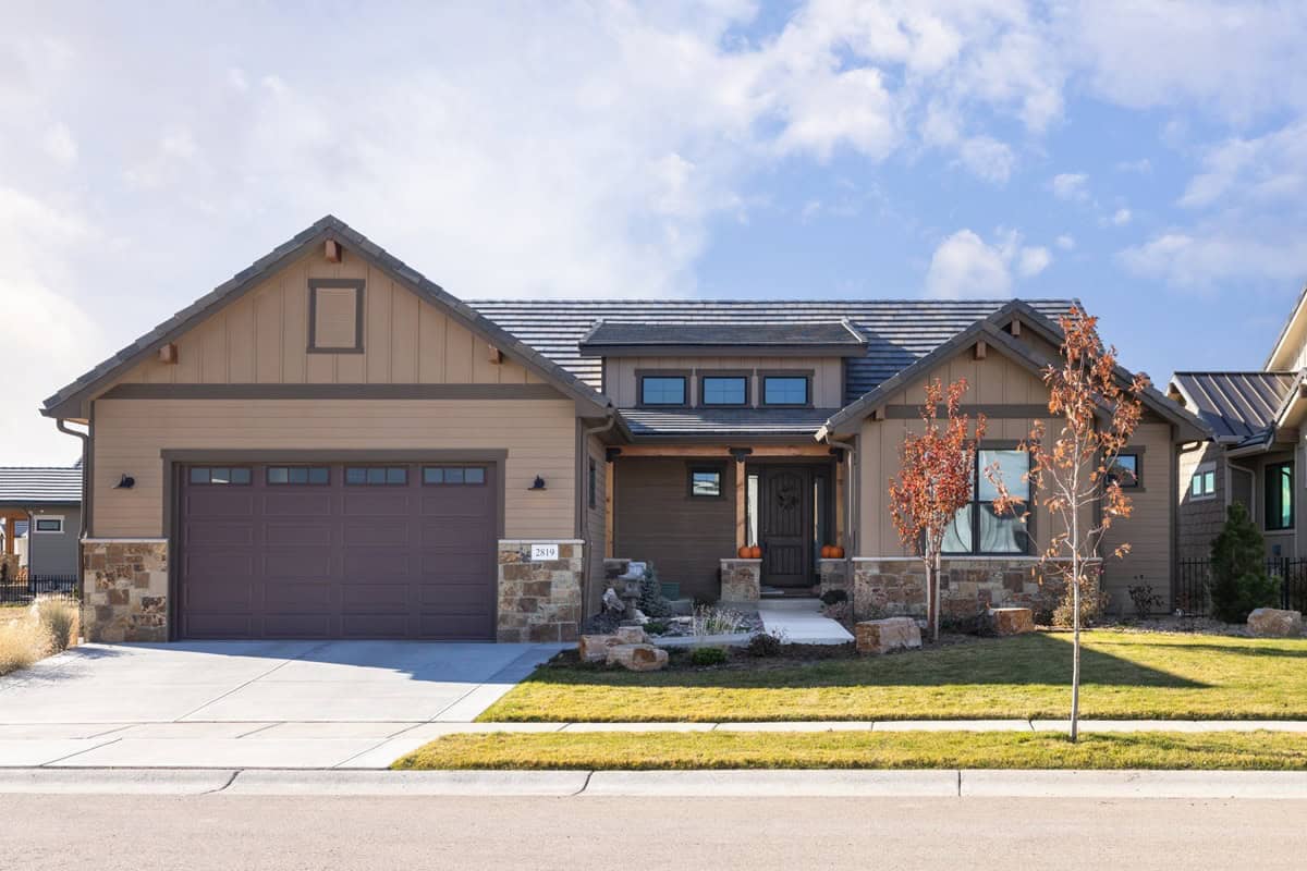 Ranch elevation with a stone base, board-and-batten gable faces, a shed dormer, and a covered front porch. 3 beds, 2,284 sq ft - Plan #161-1316.