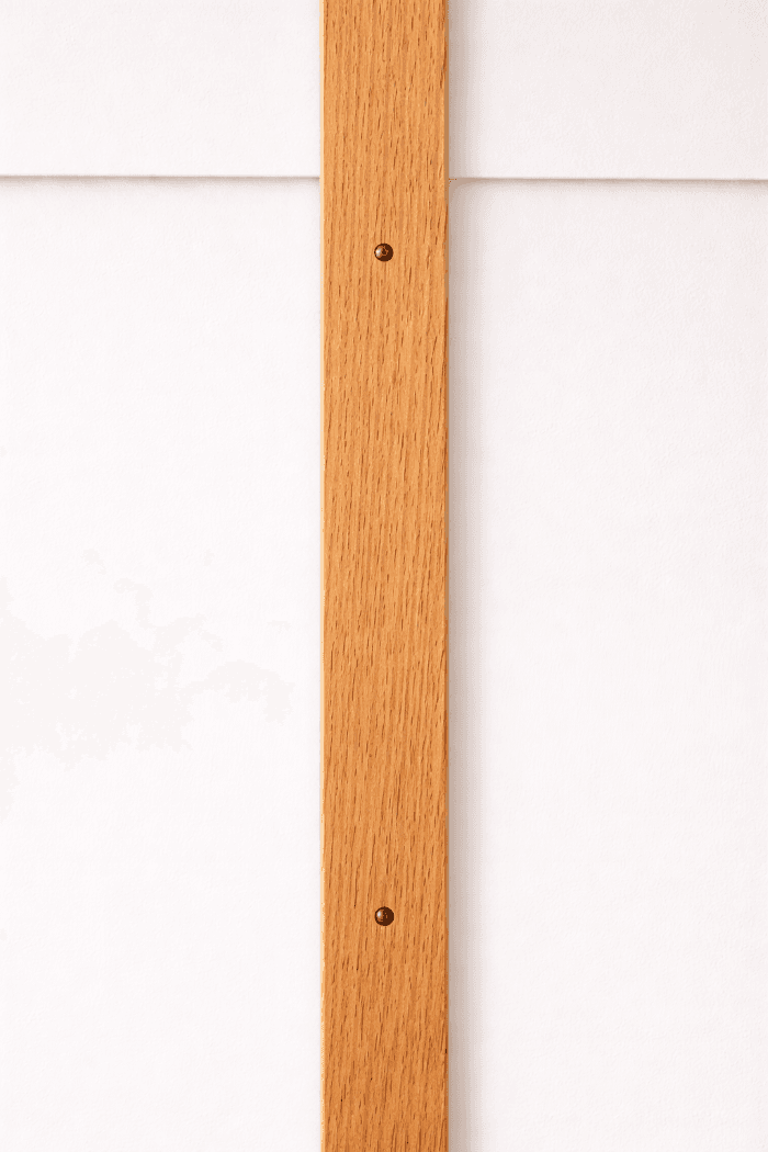 A vertical wood batten covering the seam between two siding boards.