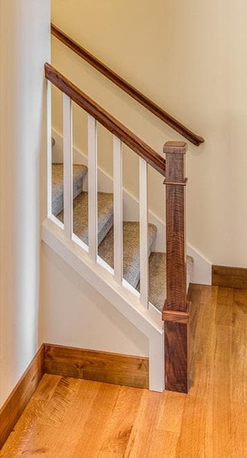 A newel post anchors the handrail at the base of a staircase.
