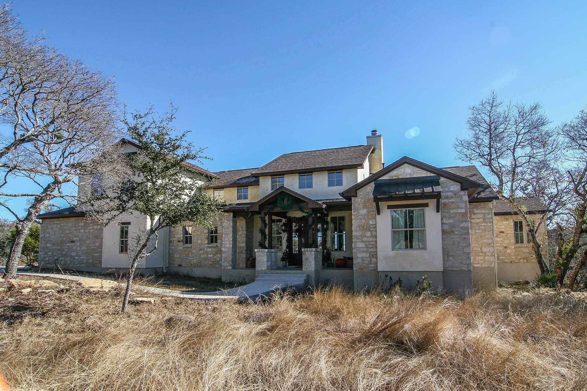 Exterior front view of Texas-style 4-bedroom home with wraparound porch and gabled rooflines