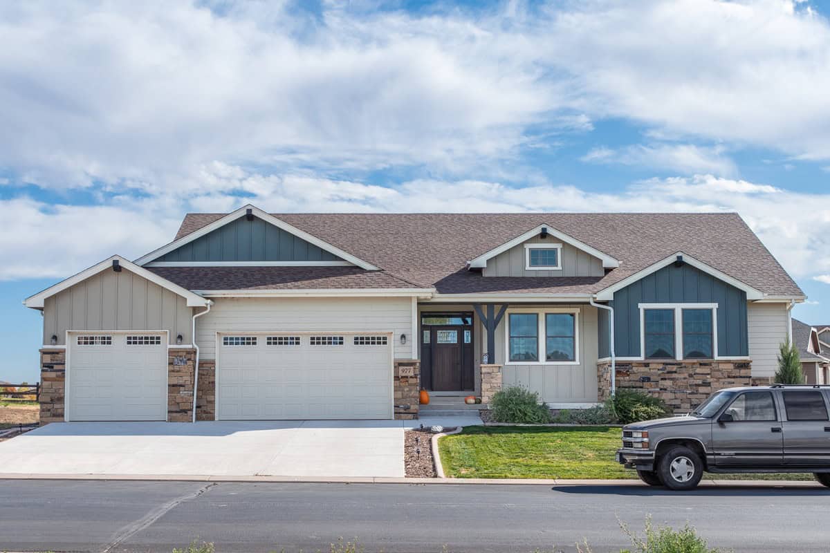 A Craftsman ranch elevation with gable dormers, stone wainscot, and a covered front porch. 3 beds, 2,561 sq ft — Plan #161-1310.