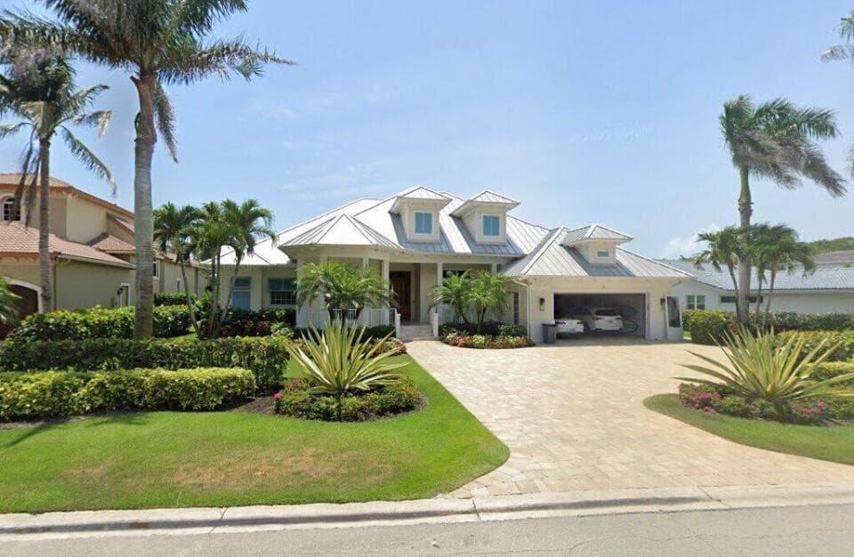 Southern-style home with covered pool deck, 2-car garage, and palm-lined landscaping